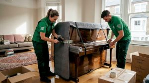 Specialist movers preparing upright piano for moving
