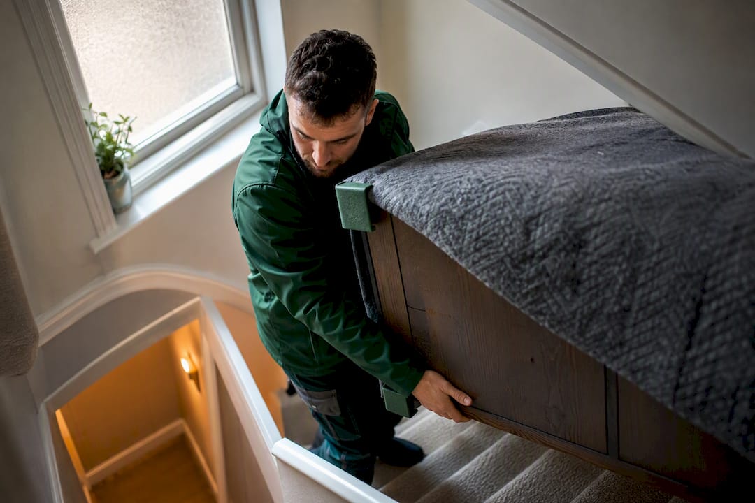 Worker protecting bulky furniture on stairs
