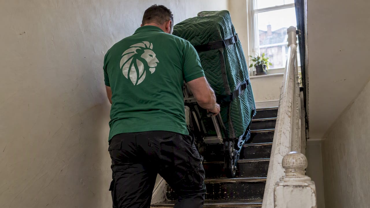 Worker using stair dolly on narrow staircase